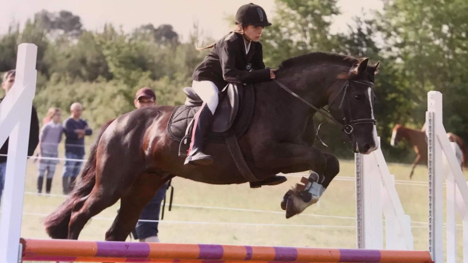 jeune fille sautant au dessus d'un obstacle à cheval